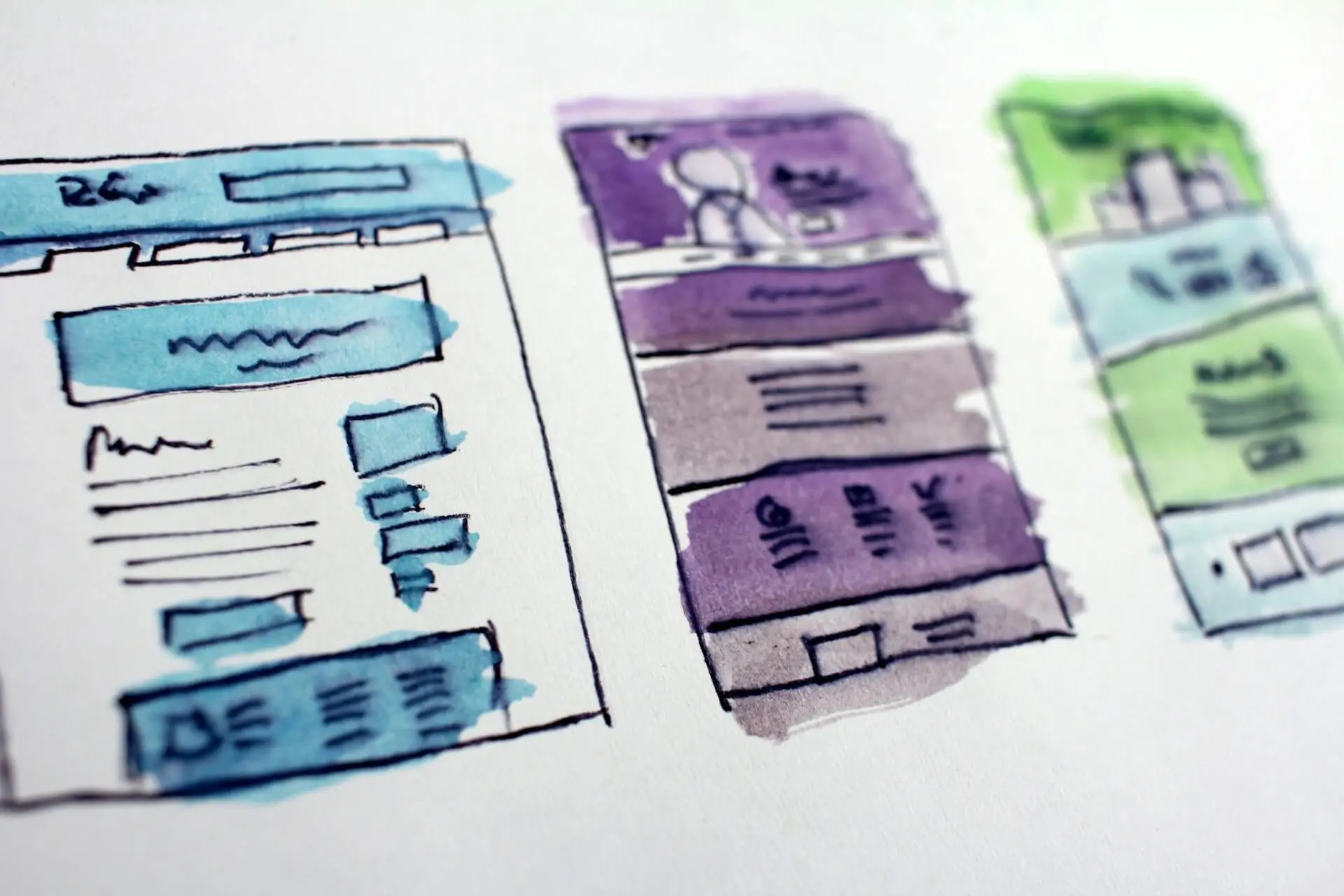 Três esboços de wireframes de sites feitos com caneta, representando o processo de criação de websites.
